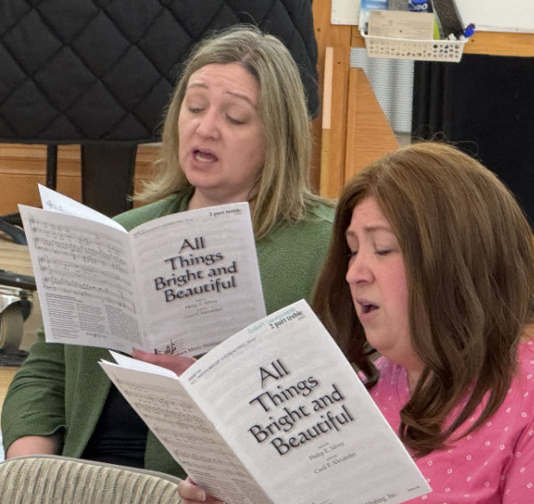 Two women singing from sheet music